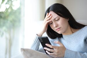 Woman experiencing back-to-school stress while checking phone