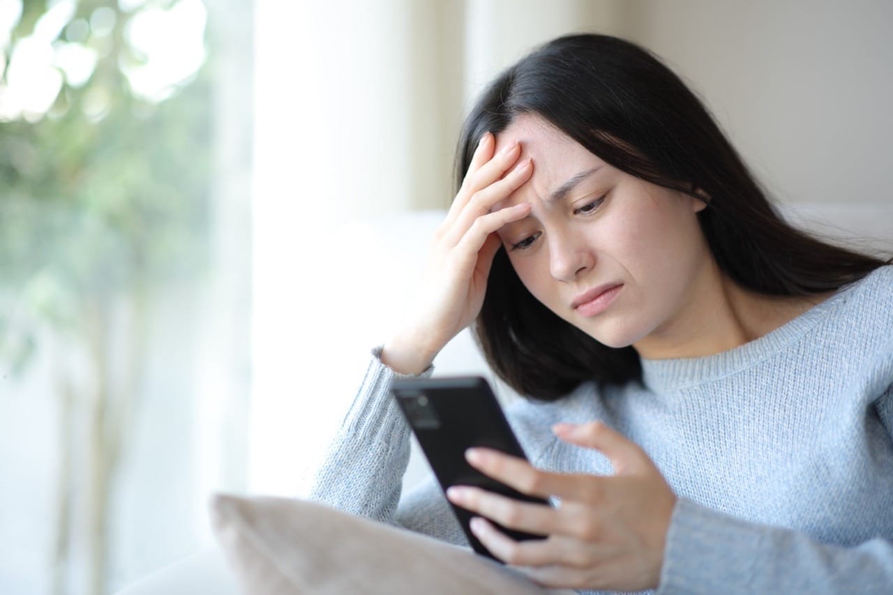 Woman experiencing back-to-school stress while checking phone